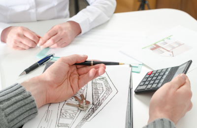 Hand shot of someone holding a calculator, sitting across from another person.